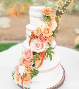 multi tiered cake covered in warm colored florals in orange, pink, and cream created by Jamie Cakes Bakery Boutique in Tucson AZ