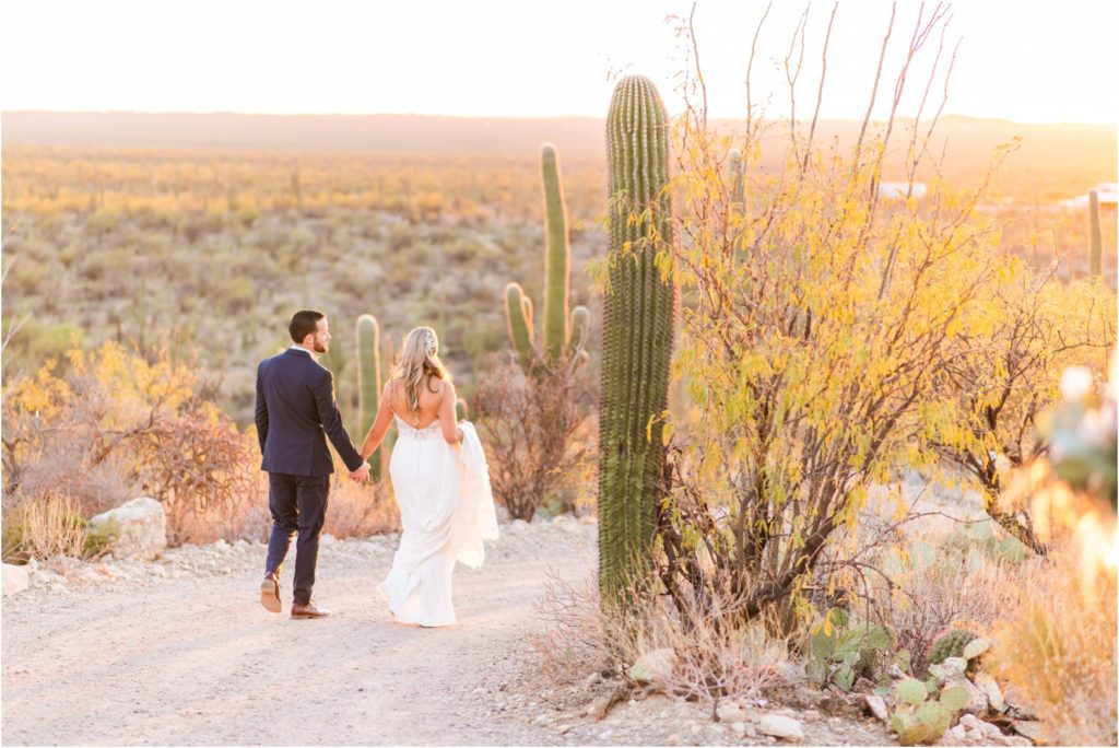bride and groom walking in desert at sunset
