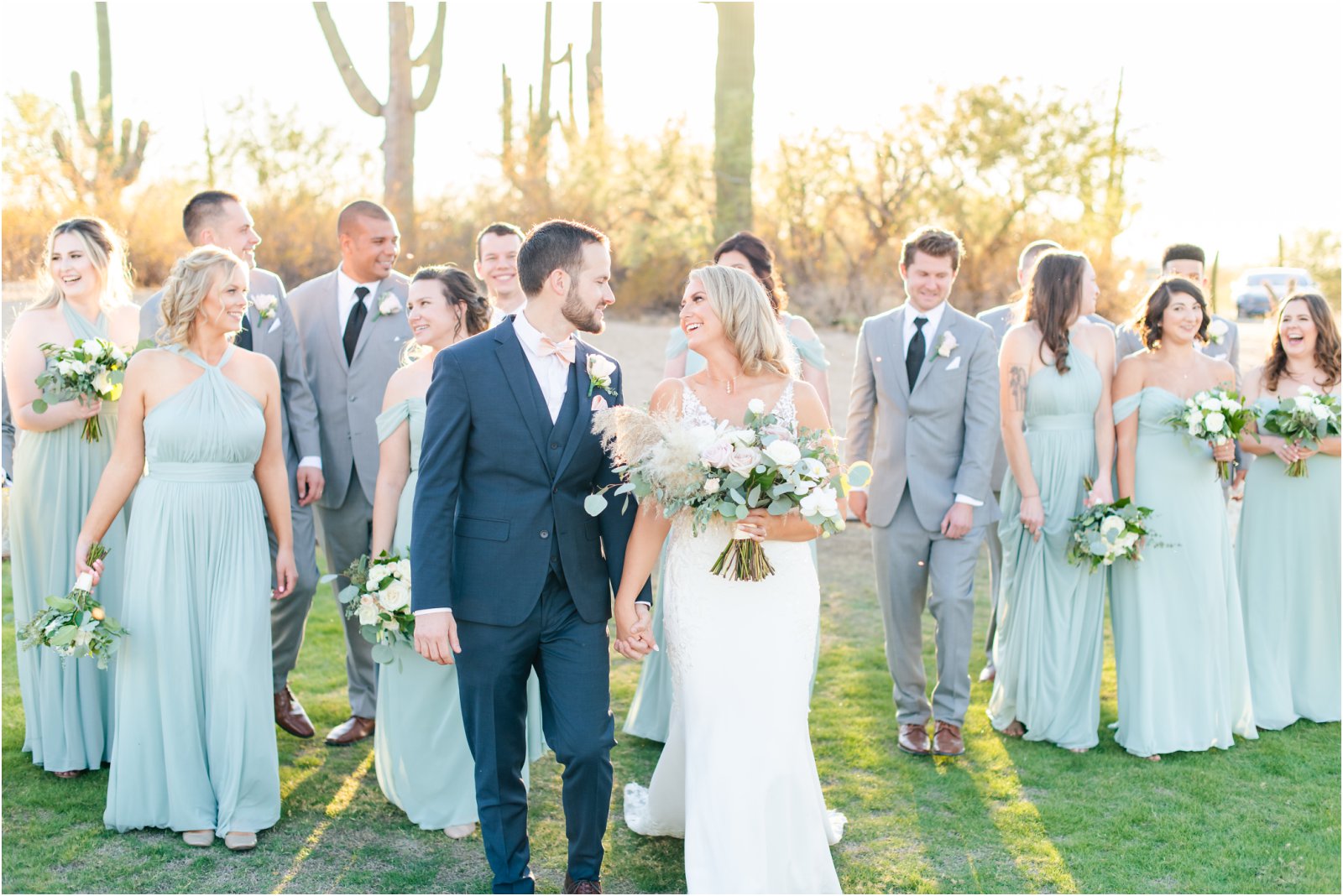 wedding couple and bridal party walking on lawn with cacti behind them at Tanque Verde Ranch barn