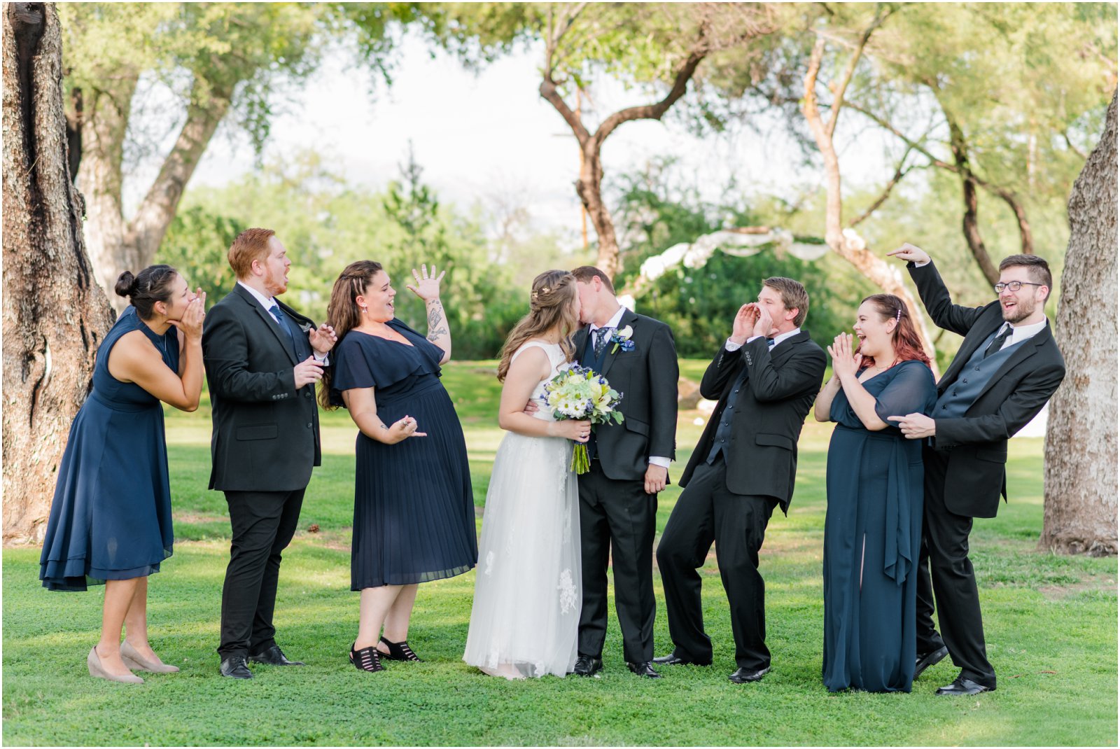 bride and groom kissing while bridal party cheers for them at La Mariposa Tucson wedding