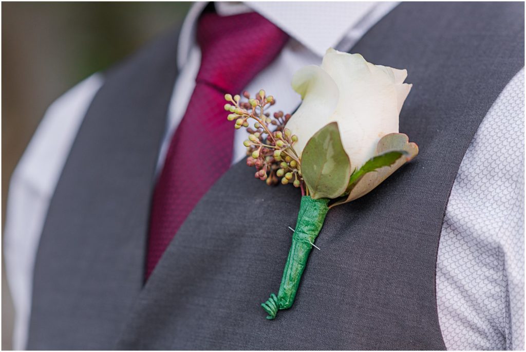 groom's boutonniere and burgundy tie
