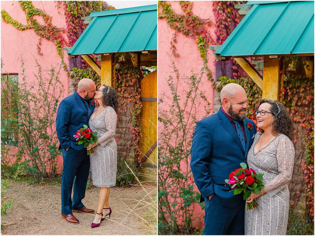 bride and groom kissing in front of pink building with ivy