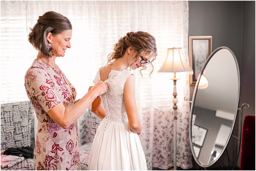 bride's mom helping her with her wedding dress
