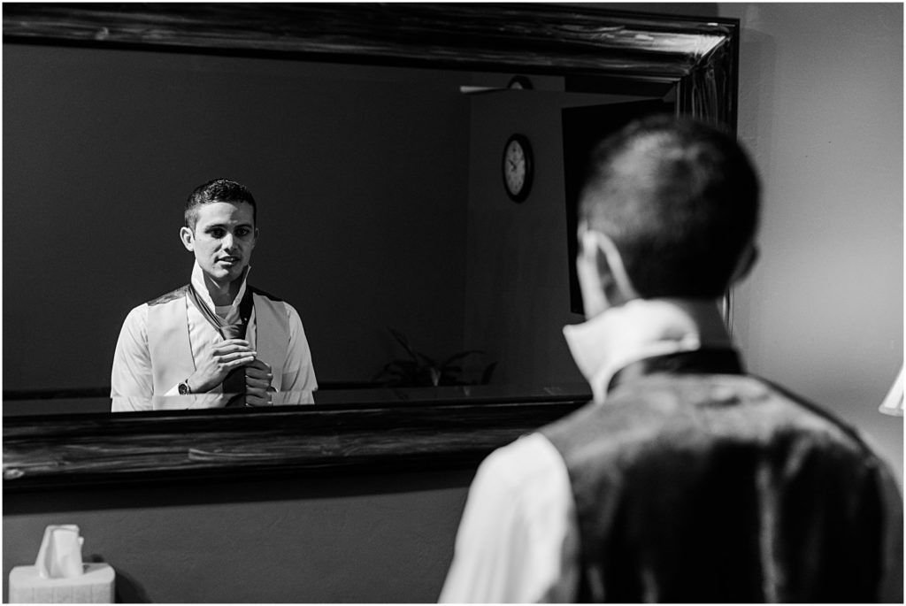 black and white image of groom getting ready in a dark room
