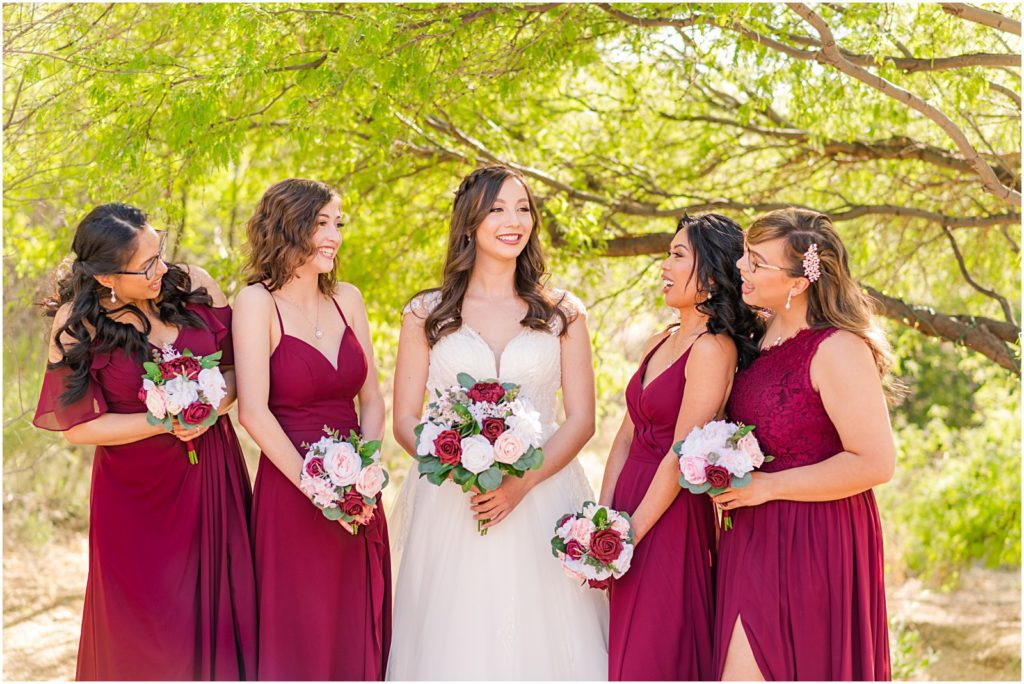 bride with bridesmaids in flowy burgundy dresses with matching bouquets