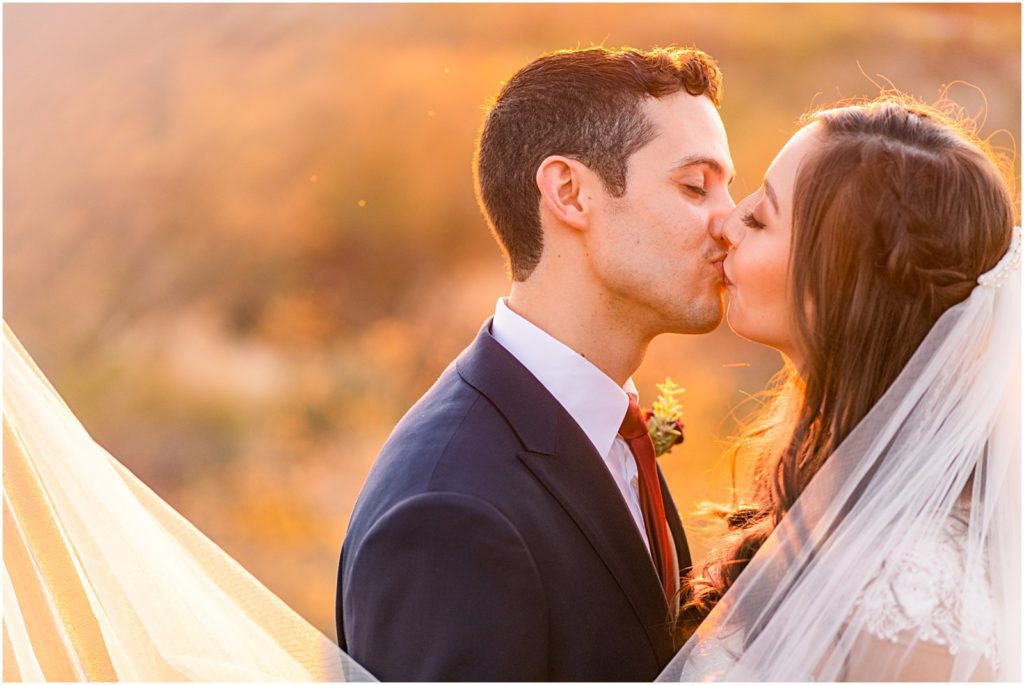 romantic closeup portrait of bride and groom kissing at sunset