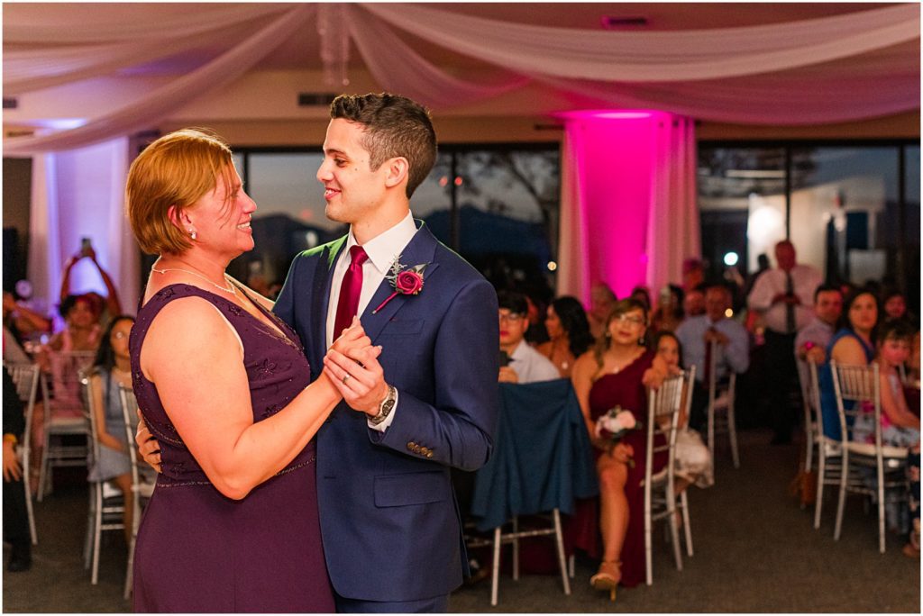groom smiling at and dancing with his mom