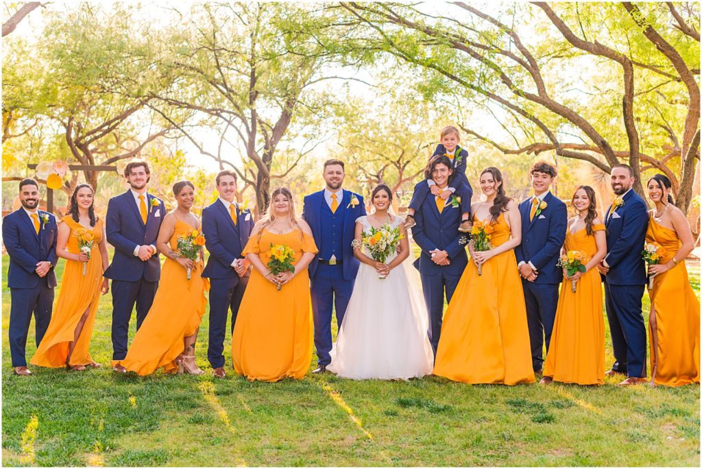 bridal party in navy and marigold yellow on green lawn