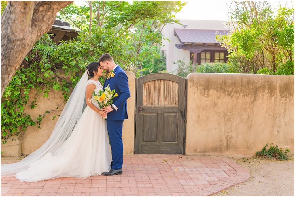 bride and groom hold each other while resting their foreheads against each other in front of wooden door