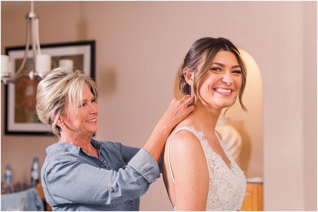 mother-in-law putting necklace on bride on her wedding day
