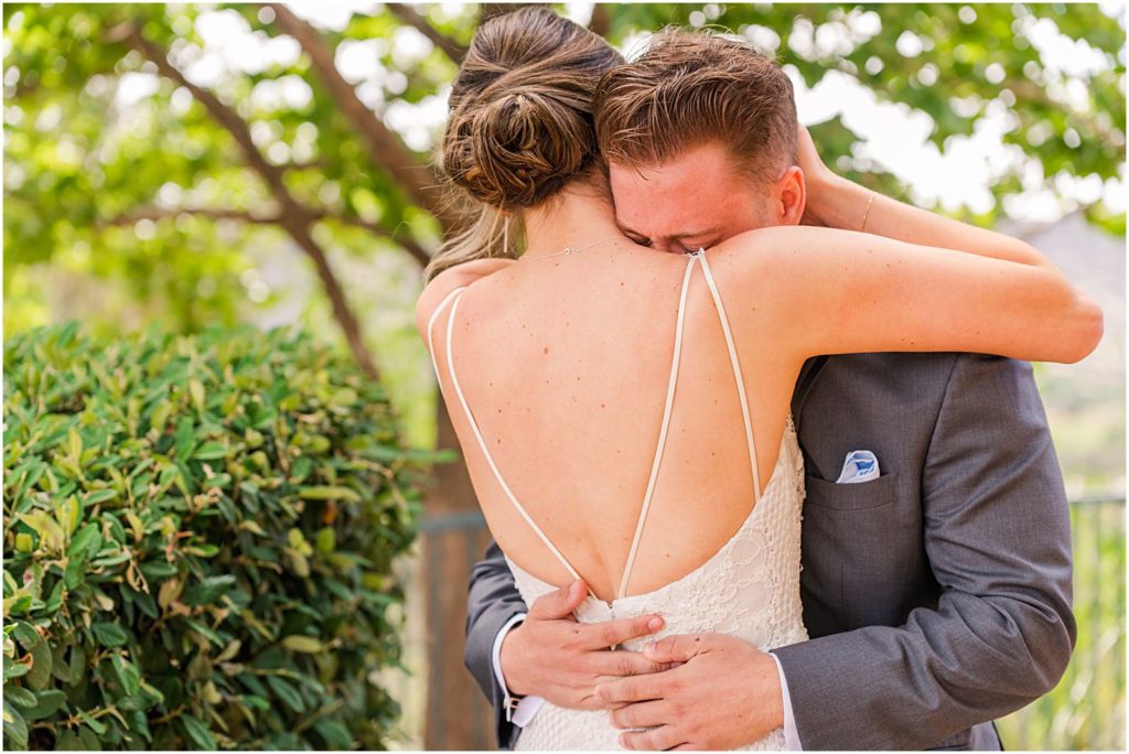 groom crying on bride's shoulder as she holds him during First Look