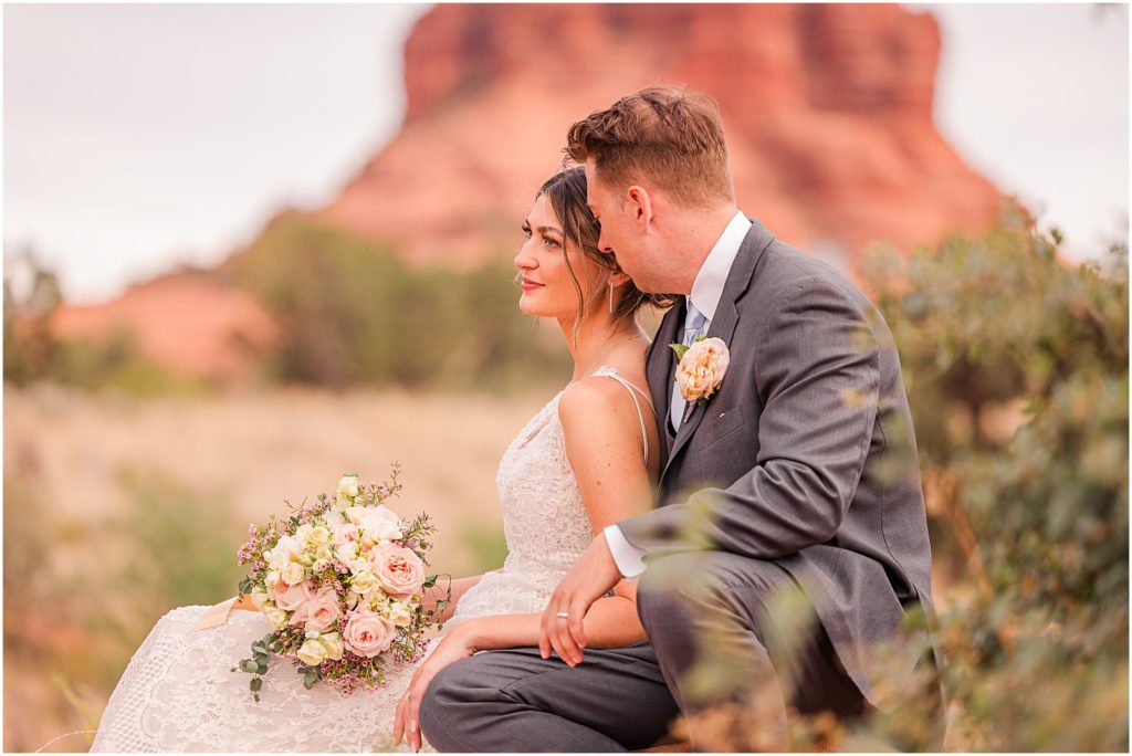 bride and groom sitting on red rock on wedding day in Sedona