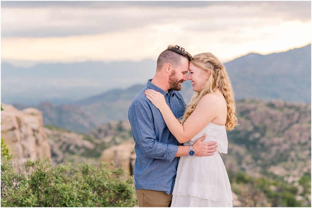 engaged couple on mountain top with stormy skies