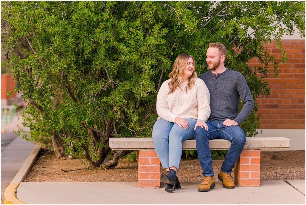 engaged couple sitting on special bench at college campus