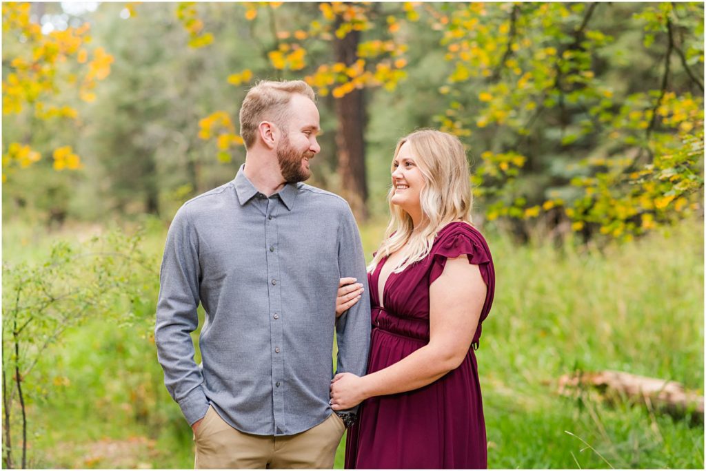 couple smiling at each other in woods
