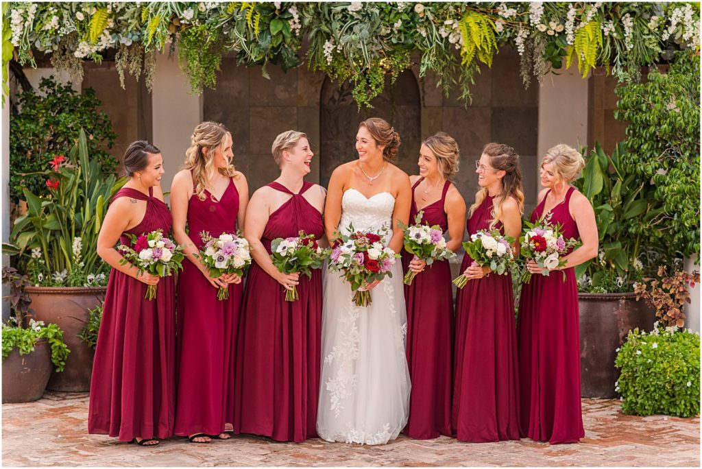 bride and bridesmaids smiling at each other in courtyard