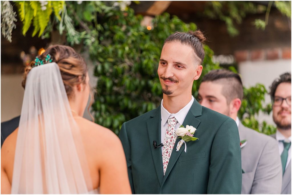 groom listening to wedding vows and smiling