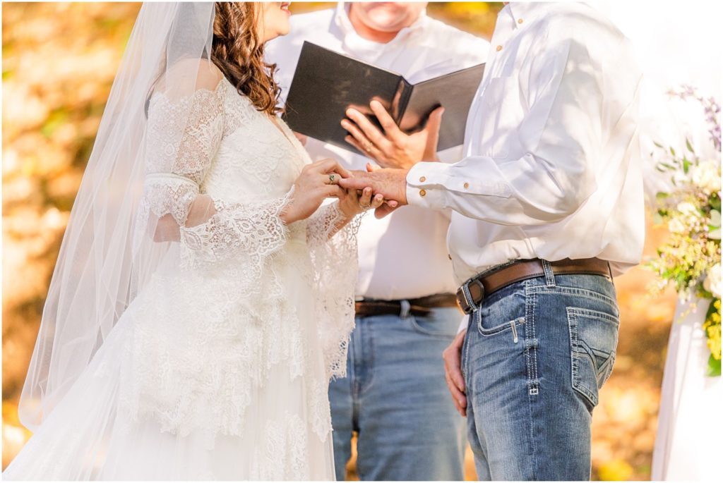 bride putting ring on groom's finger during wedding ceremony