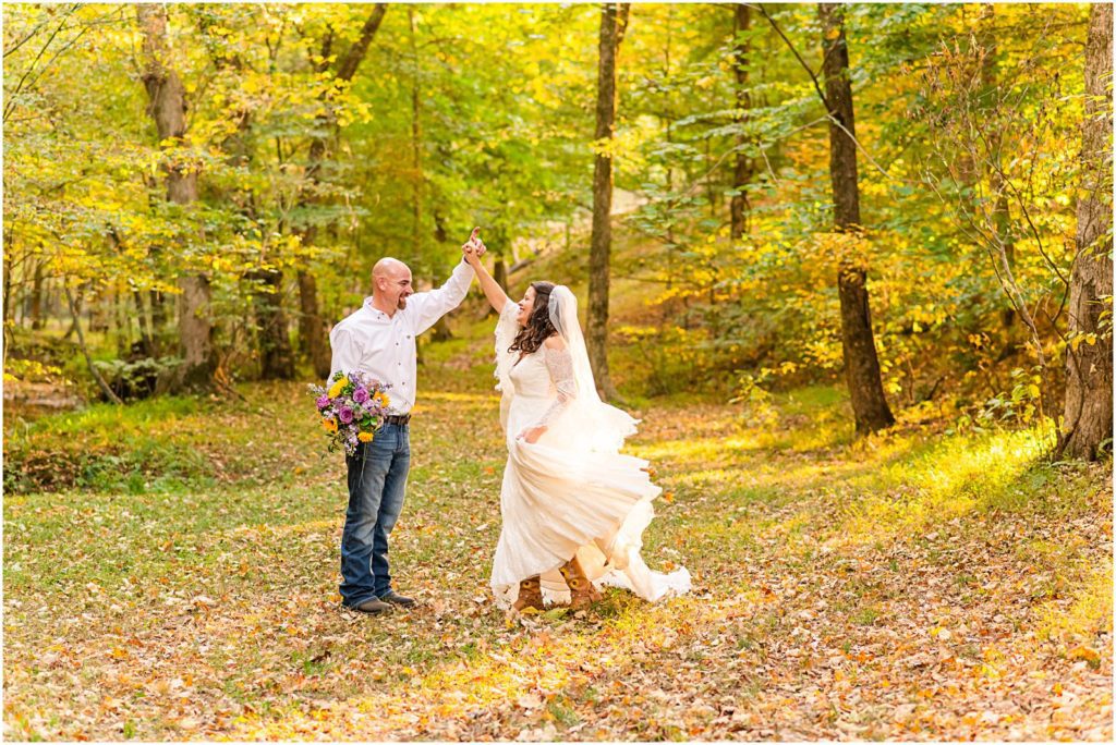 bride and groom dancing in woods in fall leaves