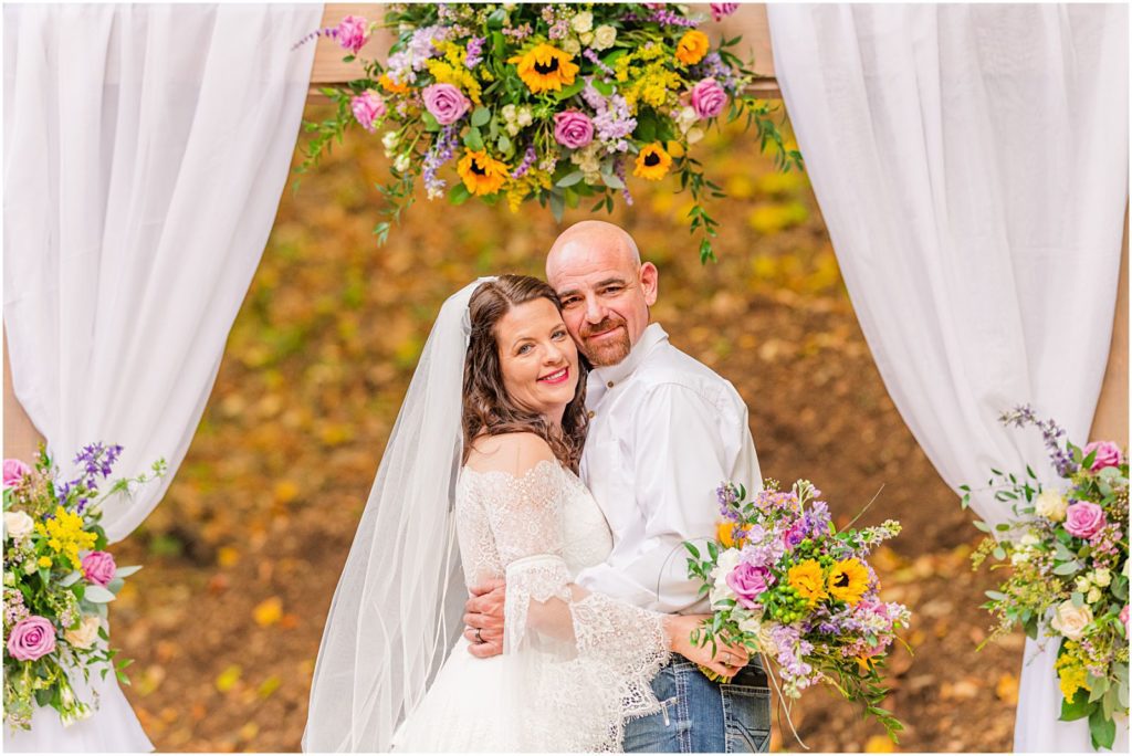 couple standing underneath ceremony archway
