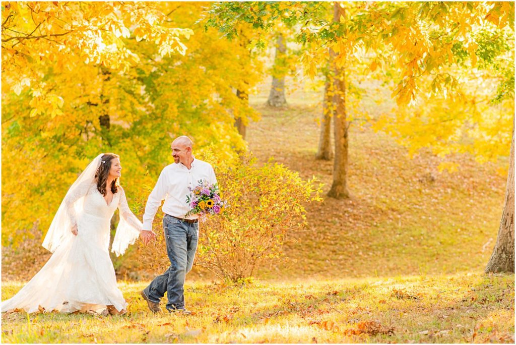 groom leading bride in woods at farm wedding in Clarksville in fall