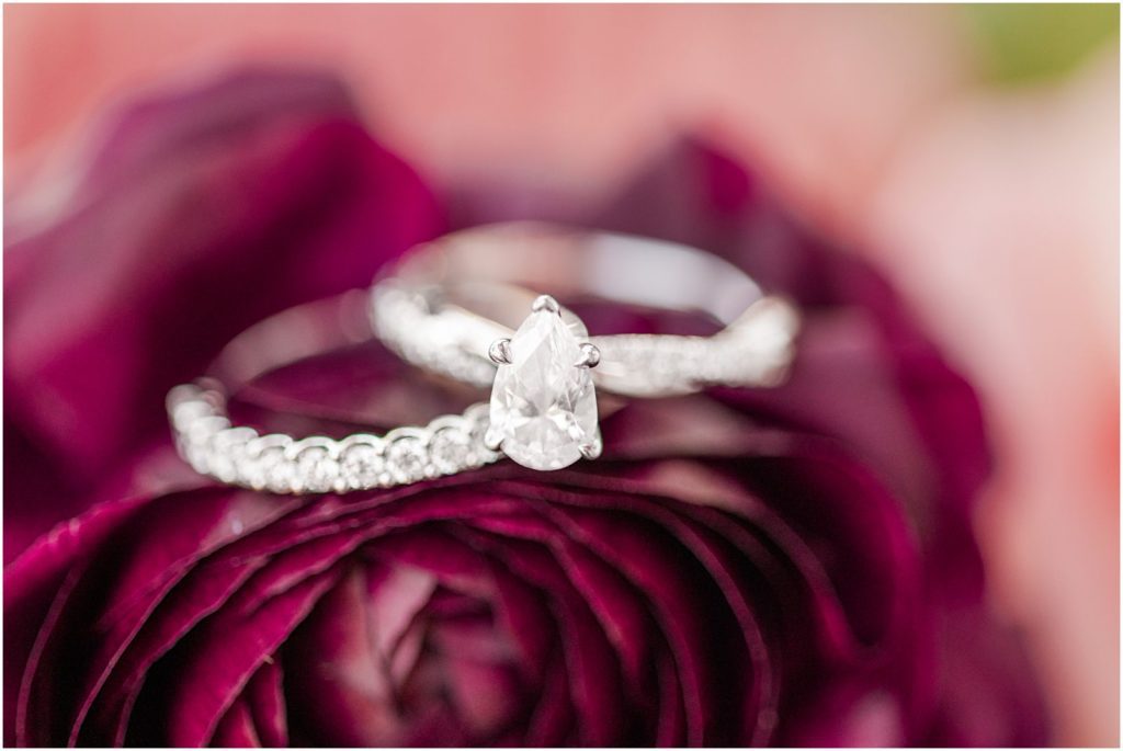 wedding rings resting on burgundy flower