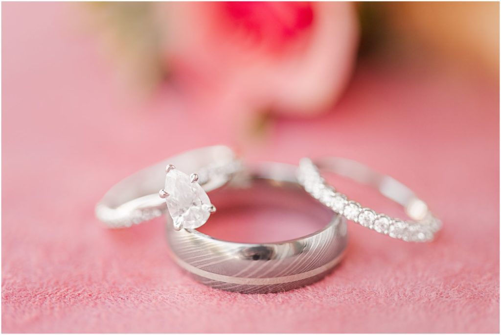 all 3 wedding bands stacked together on pink background with flowers