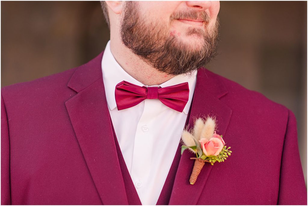 groom wearing burgundy suit with matching bowtie