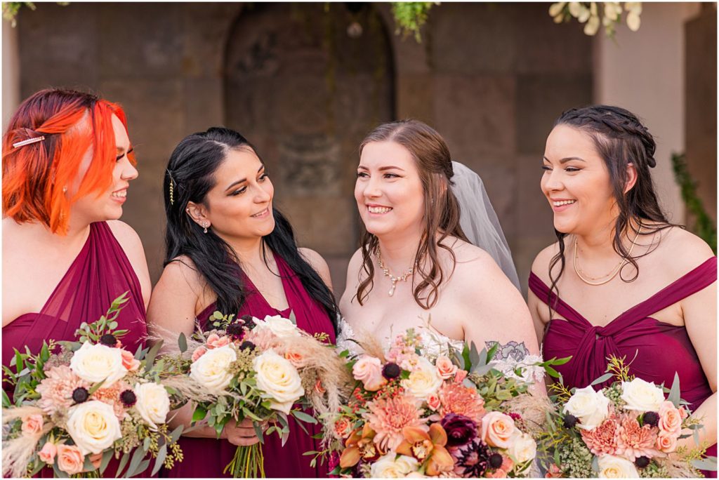 bridesmaids smiling and laughing at bride holding bouquets