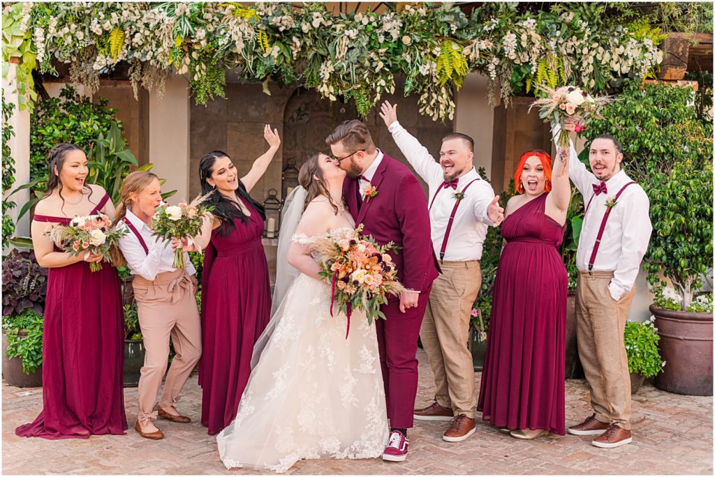 wedding party cheering as bride and groom kiss