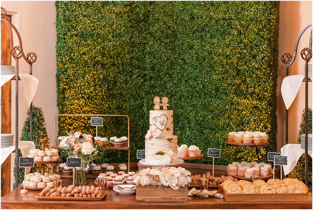 dessert table with tiered cake, cupcakes, cookies, and churros by Ambrosia Cakes