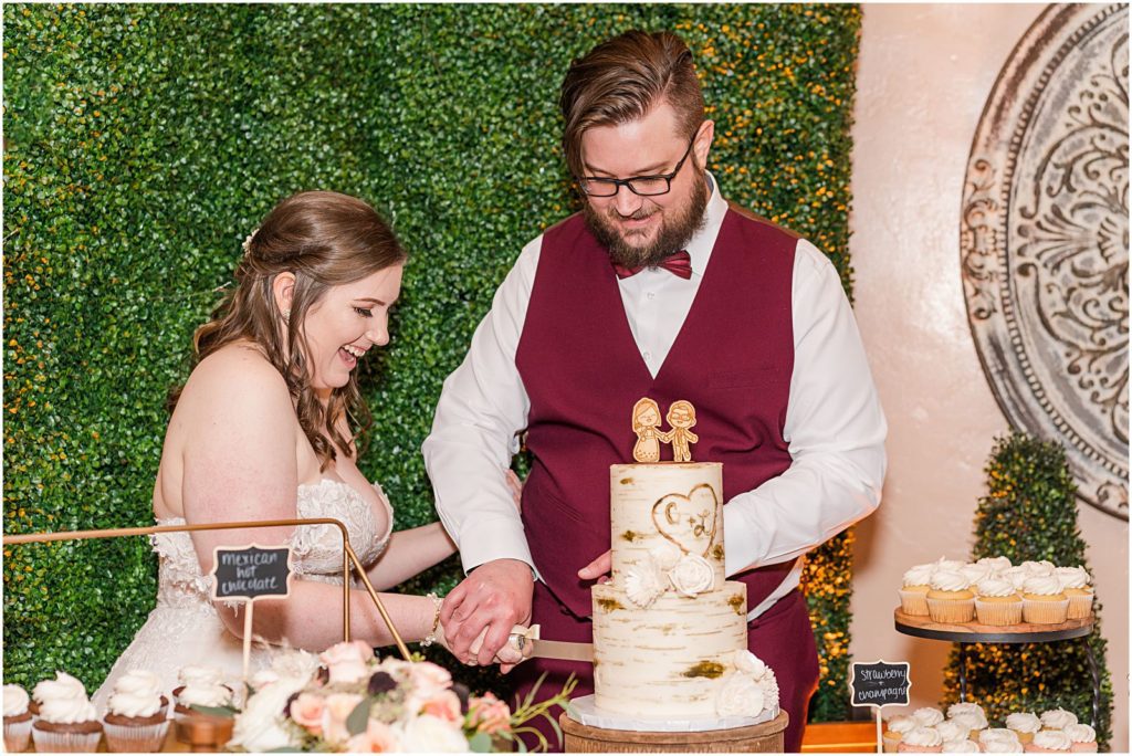 bride and groom laughing as they cut their wedding cake
