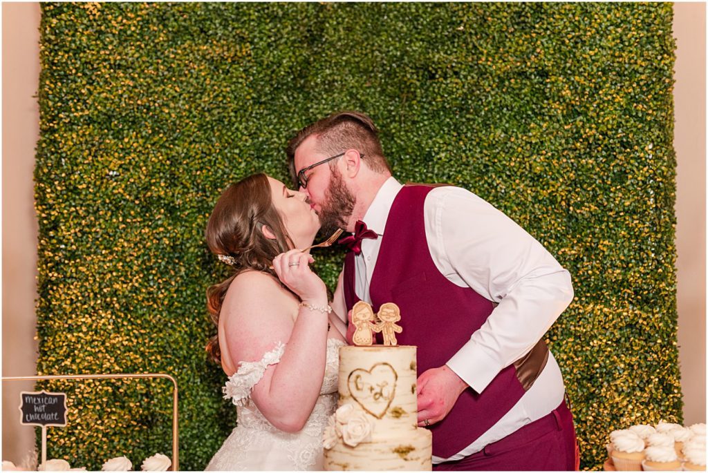 bride and groom kissing behind wedding cake