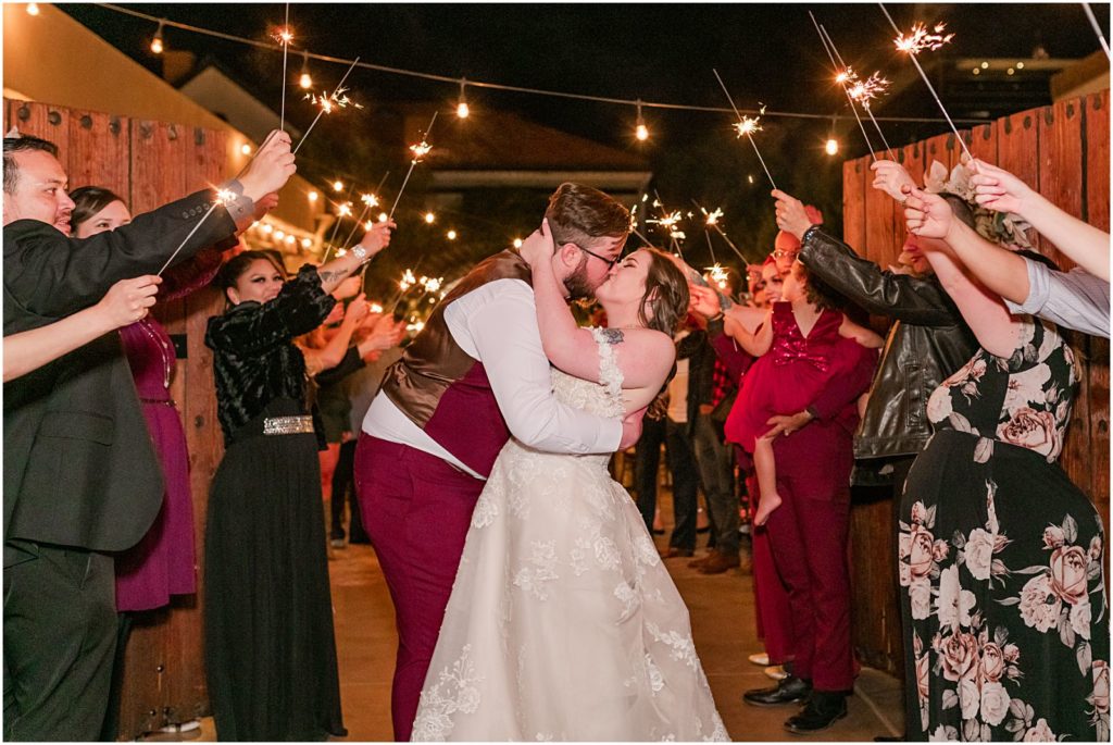 bride and groom kissing surrounded by sparklers at reception at night