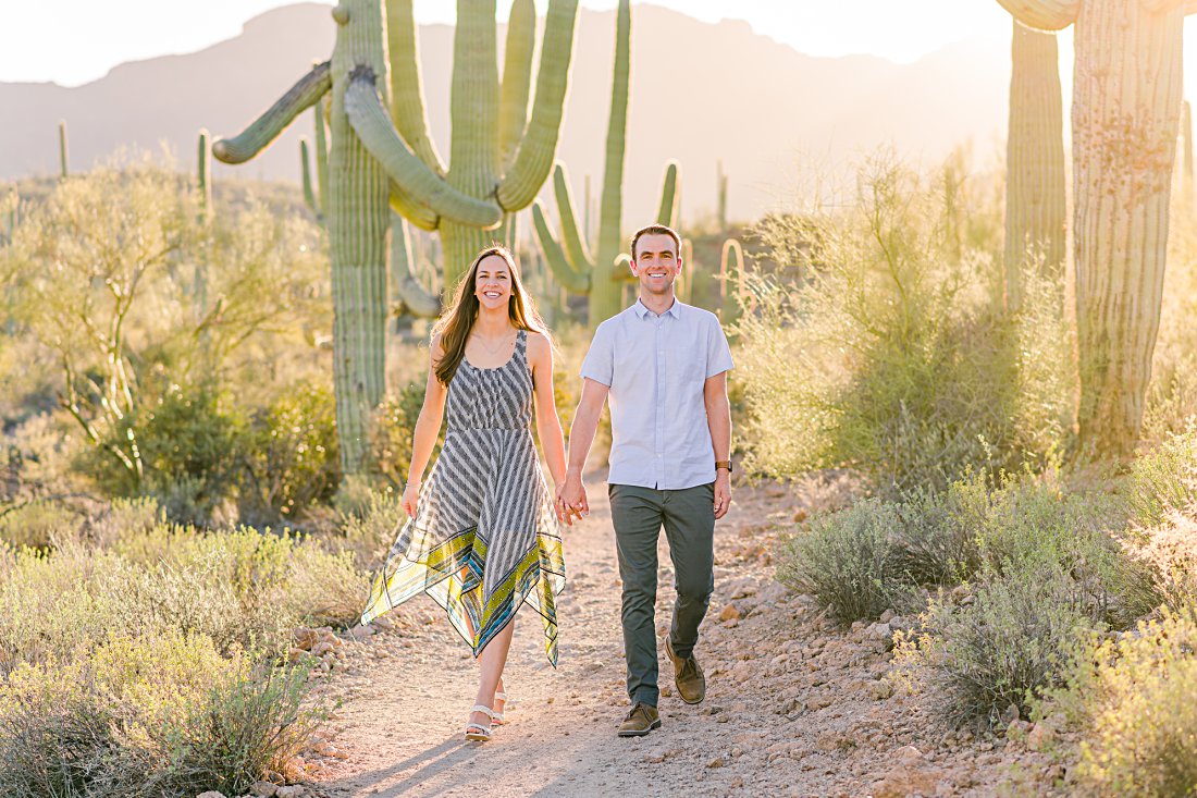 engaged couple holding hands and walking in winter engagement photos in desert