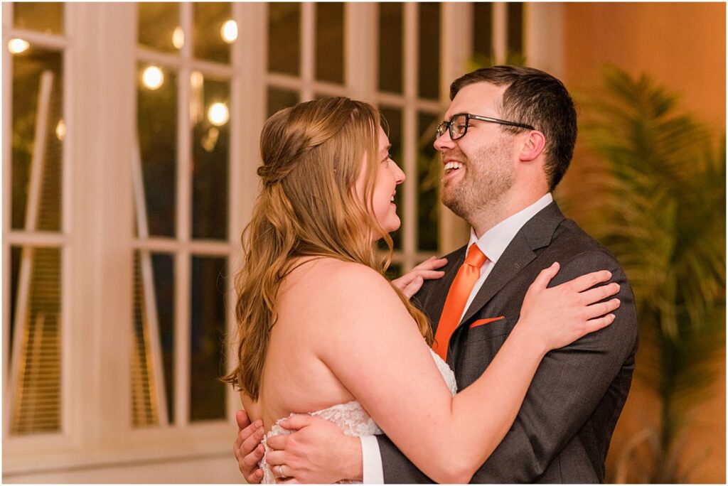 groom laughing while he dances with his bride
