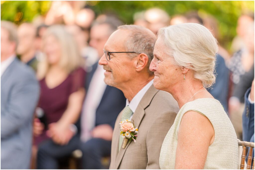 parents of the groom smiling as they watch ceremony