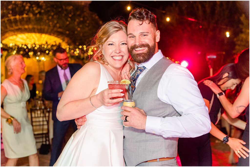 couple smiling on dancefloor with drinks in hand at reception
