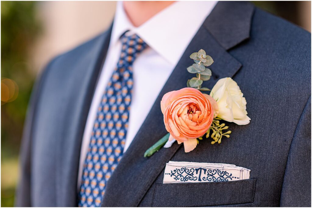 groom with navy suit and coral floral boutonniere