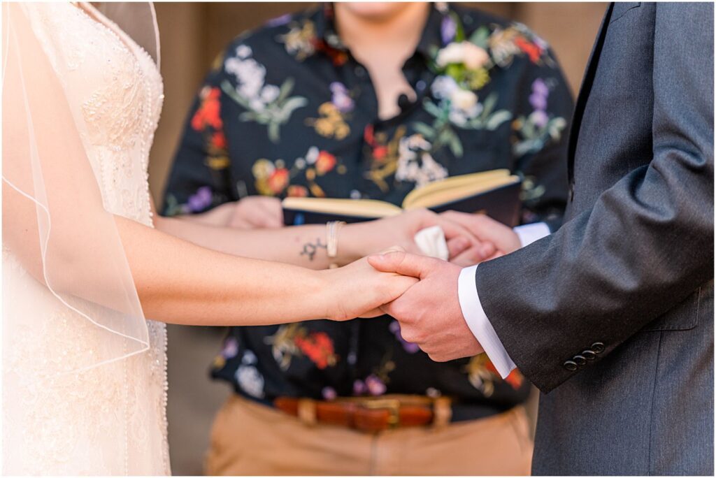 bride and groom hold hands and exchange rings