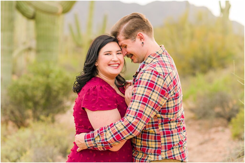 couple wearing burgundy outfits in desert engagement photos