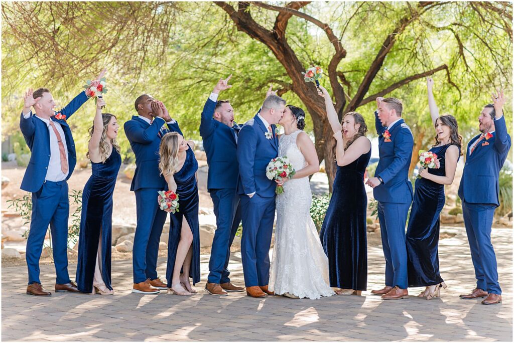 bride and groom kiss while wedding party celebrates and cheers