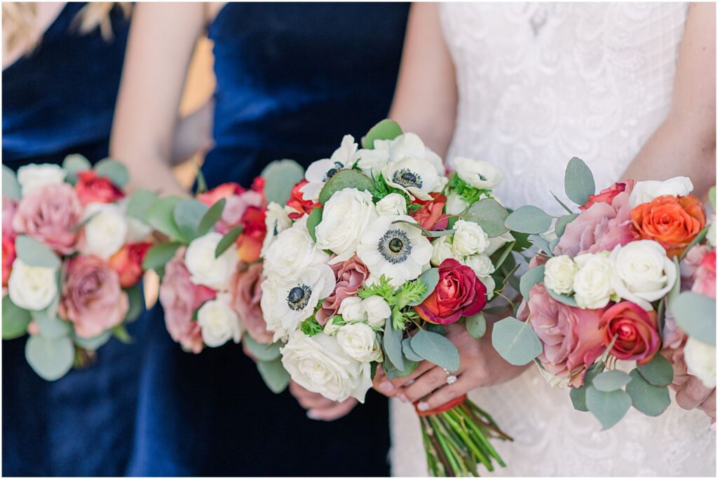 bouquets of white, red, and pink flowers with navy dresses behind them