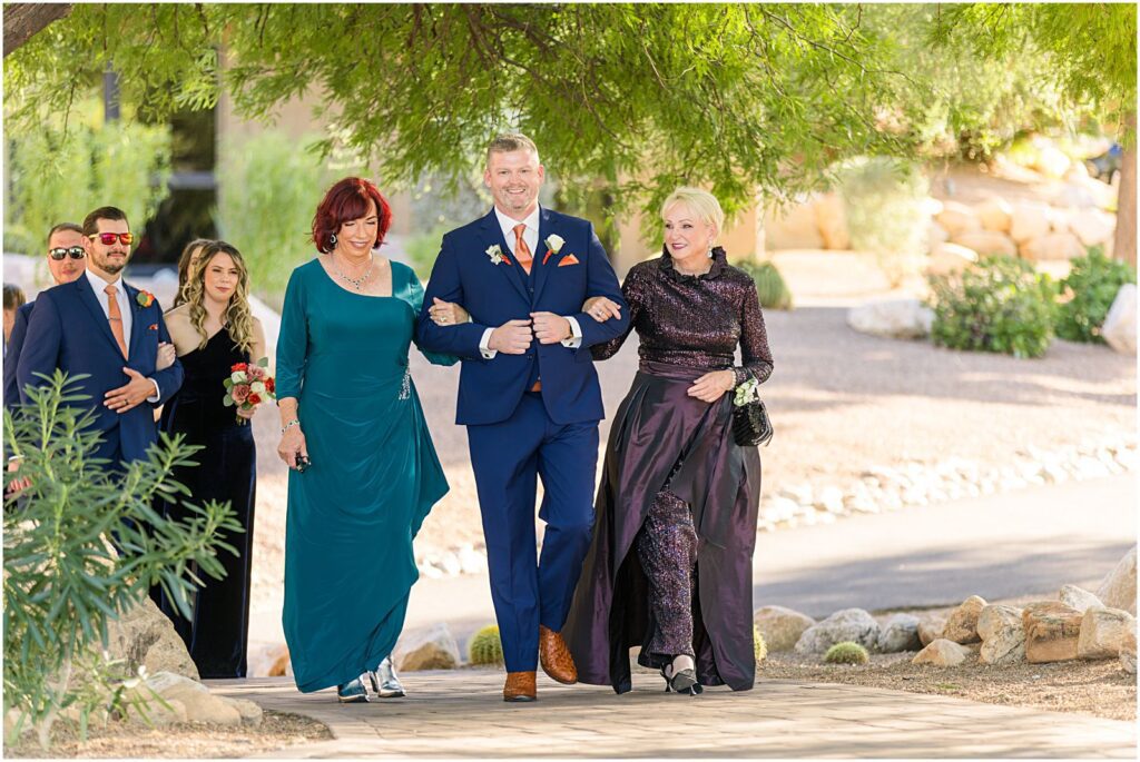 groom escorting his mother and mother-in-law down the aisle