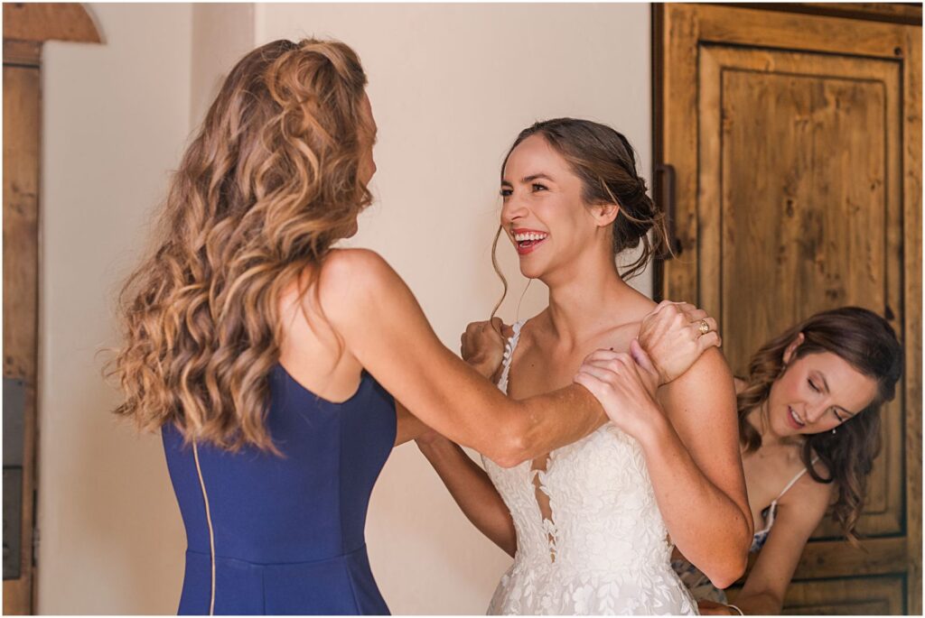 bride smiling at mom getting into her wedding dress